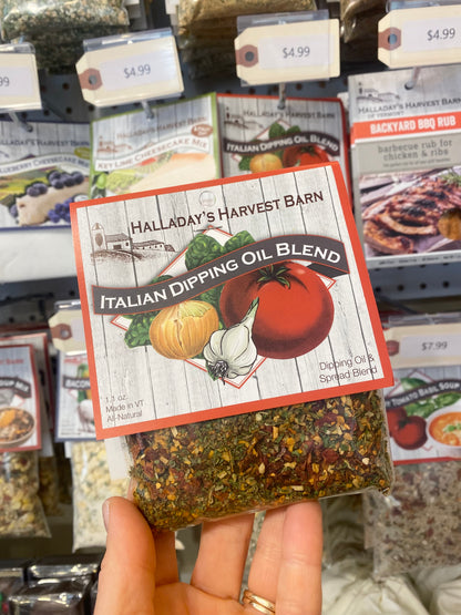 Hand holding a package of Halladay's Harvest Barn Italian Dipping Oil Blend in a store setting.