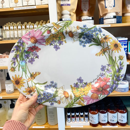 Person holding an oval tray with floral design in a store setting