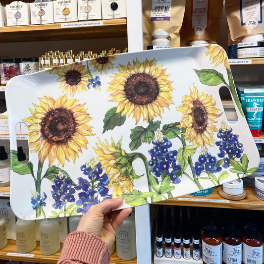 Hand holding a tray with sunflower and bluebonnet design in a store setting.
