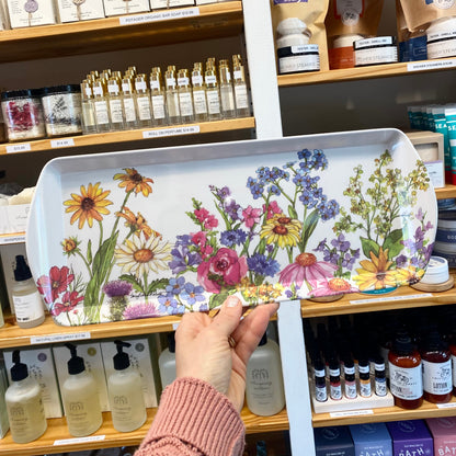 Person holding a decorative tray with floral design in a store setting