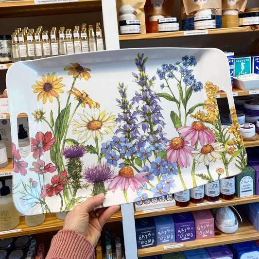 Hand holding a tray with floral design in front of a store shelf.