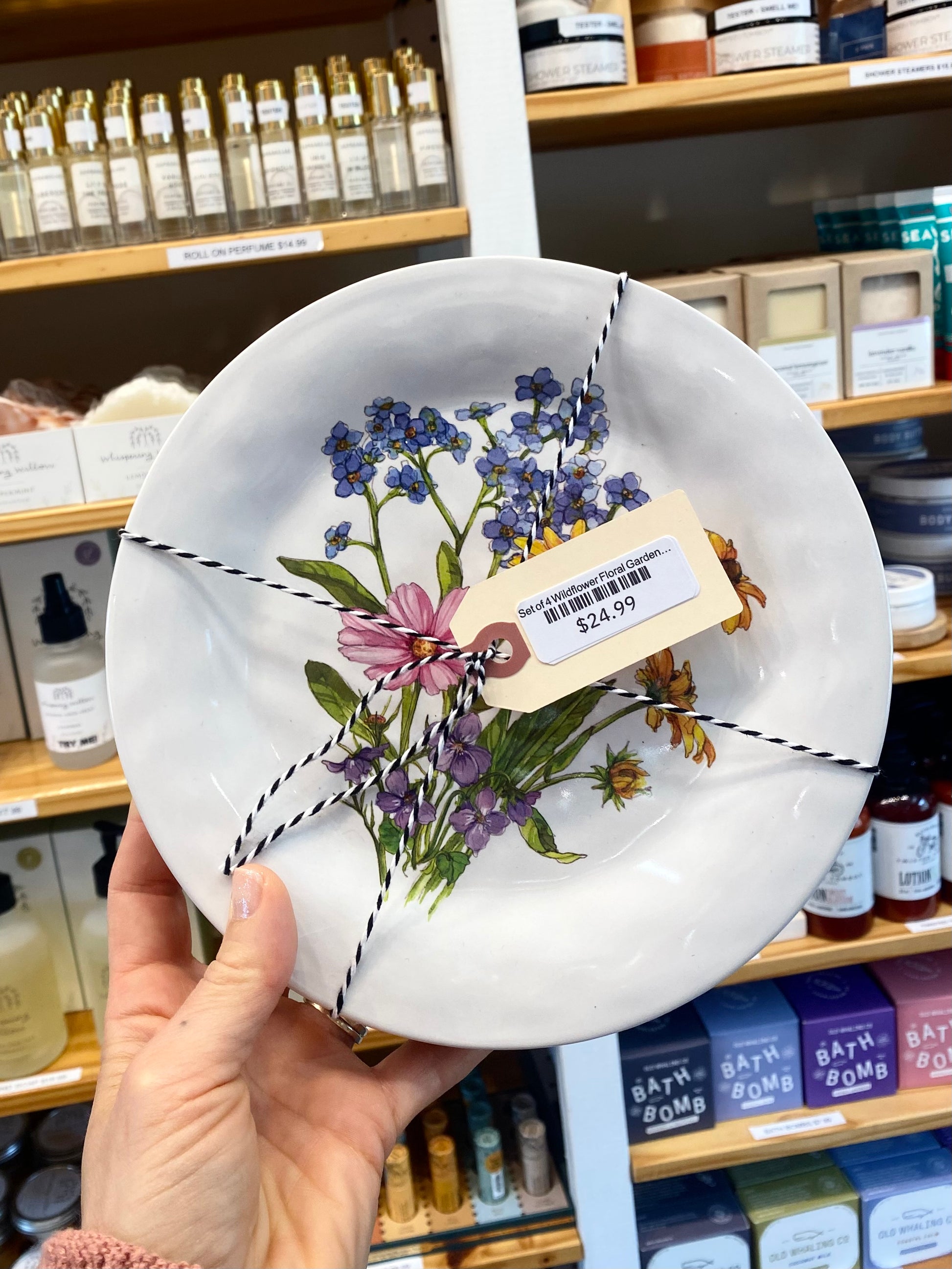 Decorative plate with floral design held in front of a store shelf.