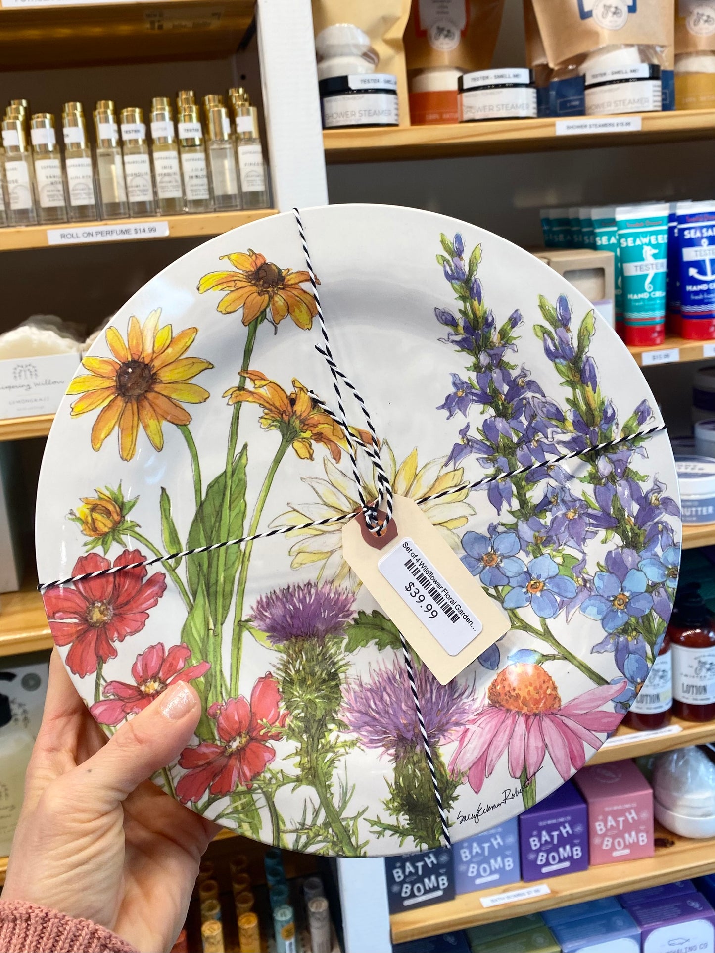 Plates with floral design held in front of a store shelf.