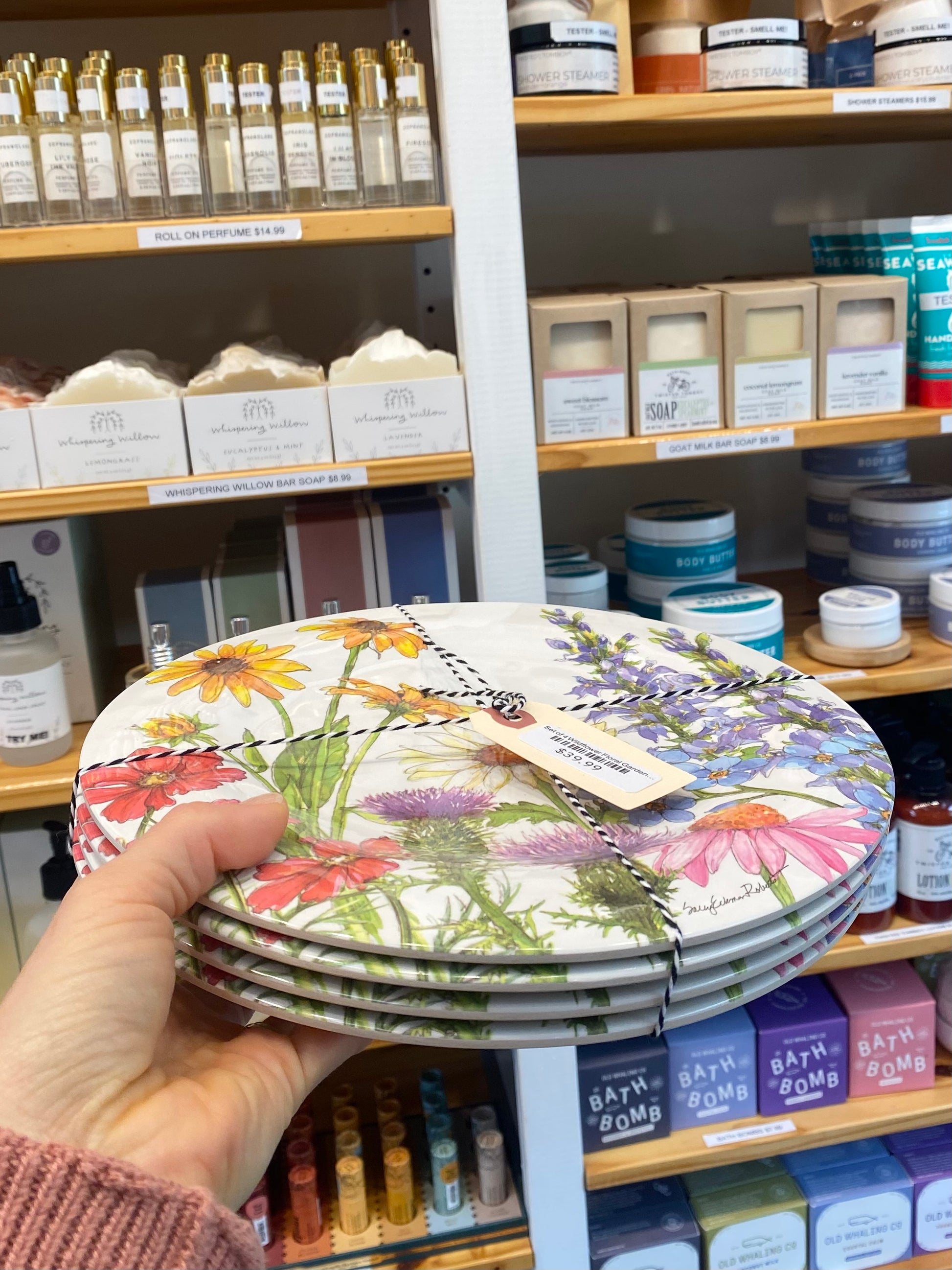 Stack of floral plates held in front of a store shelf with various products.