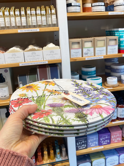 Stack of floral plates held in front of a store shelf with various products.