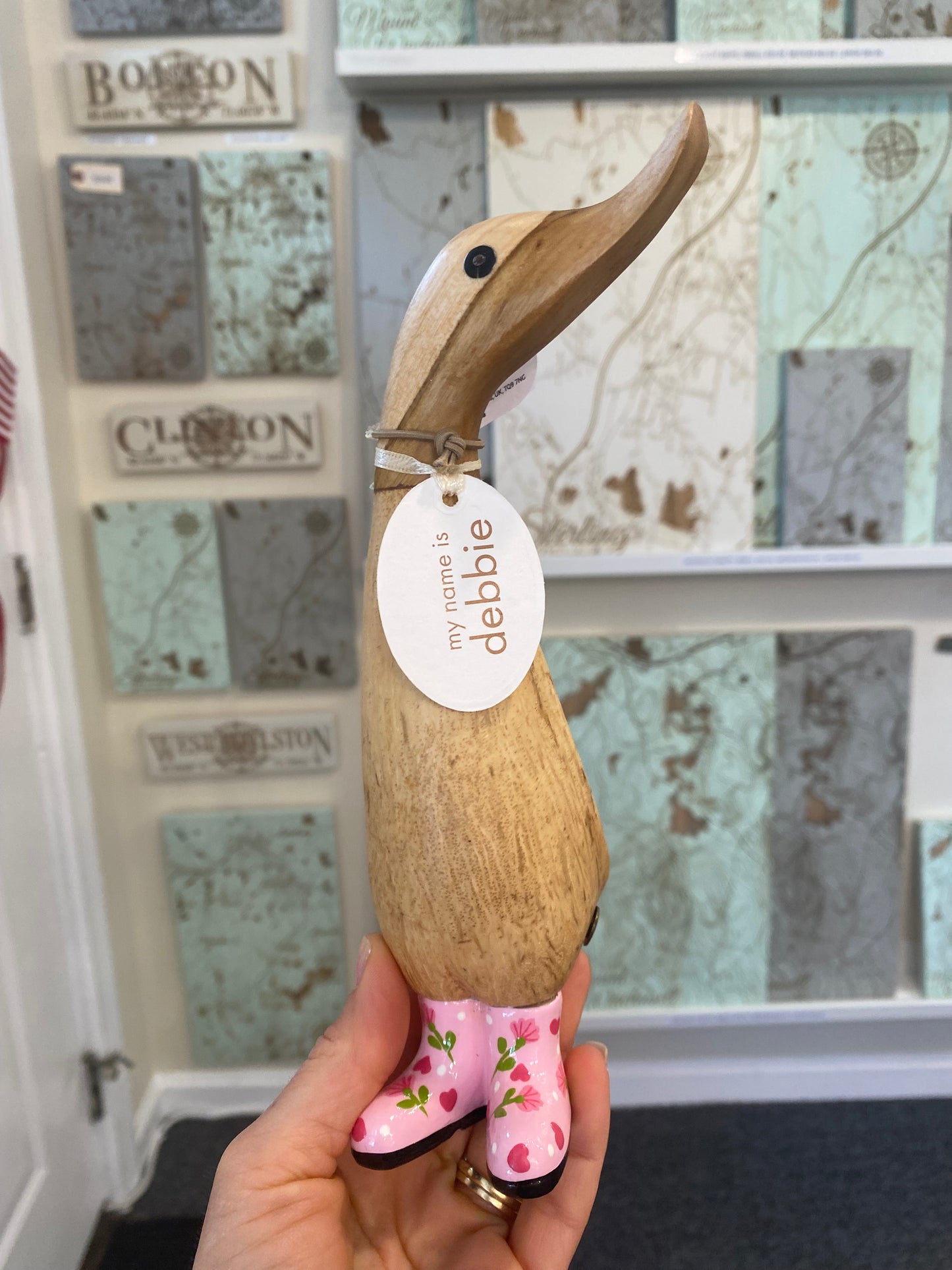 Wooden duck figurine with pink flower boots on a decorative background