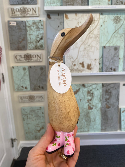 Wooden duck figurine with pink flower boots on a decorative background