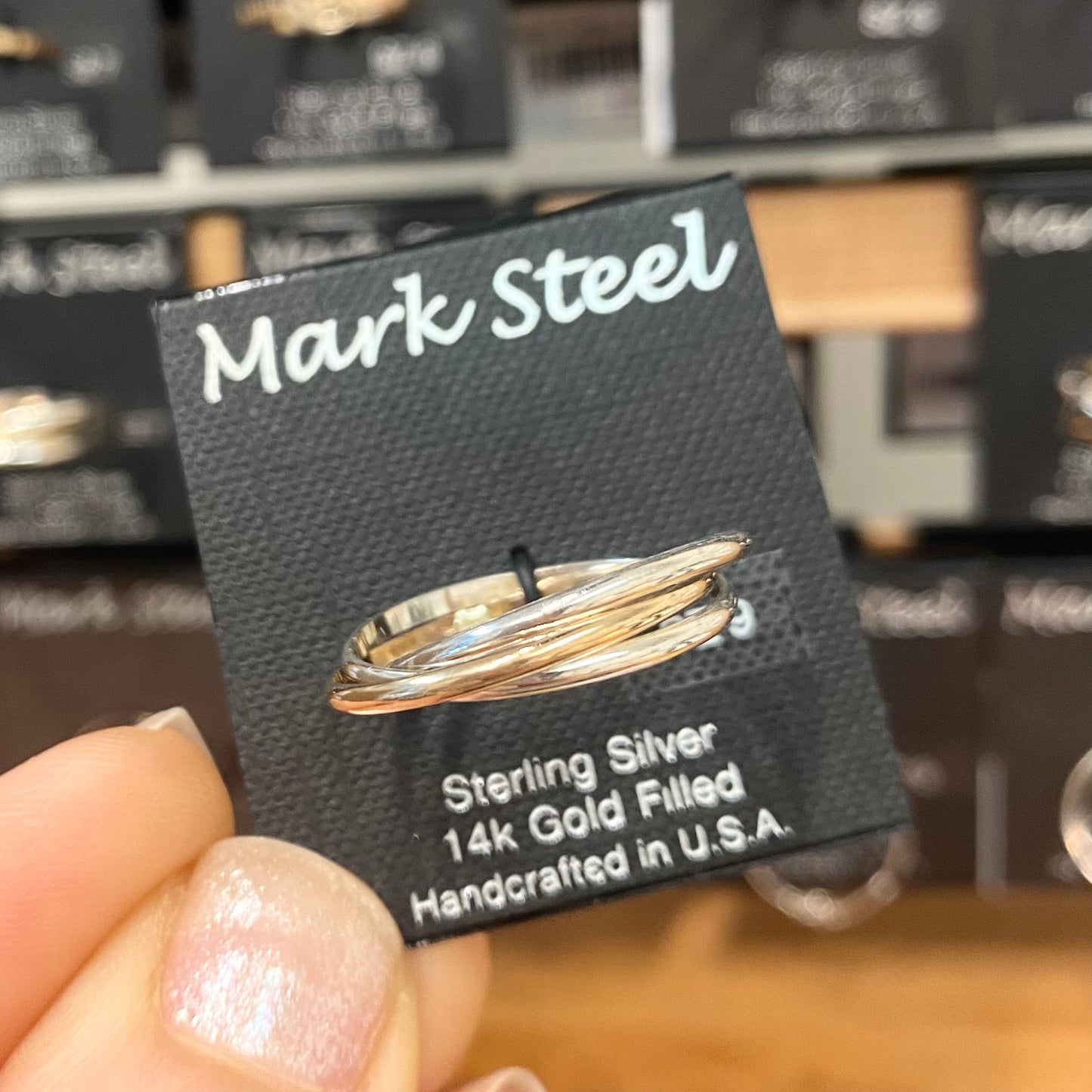 Silver and gold ring on a 'Mark Steel' branded card with product details.