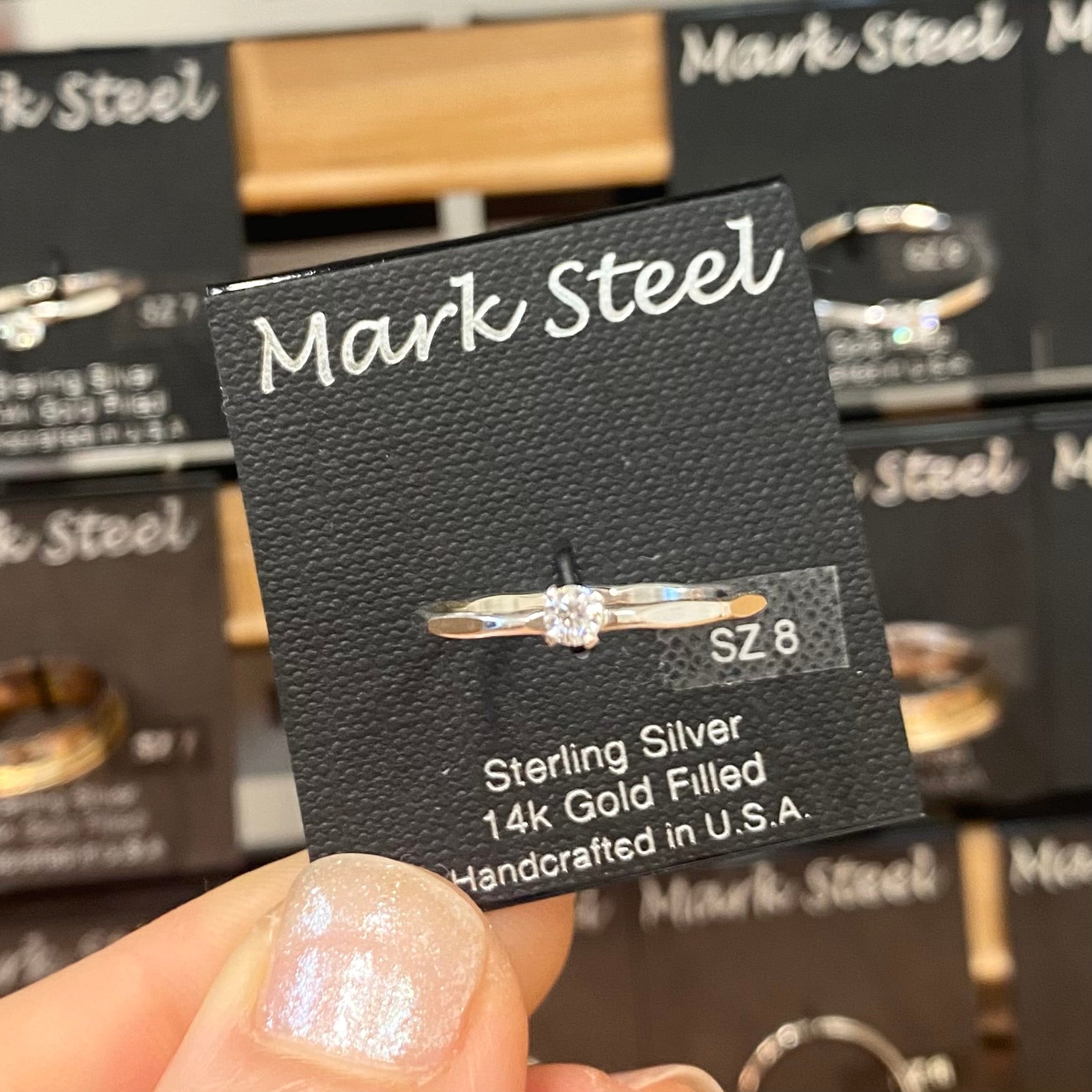 Silver ring on a Mark Steel branded card with multiple cards in the background