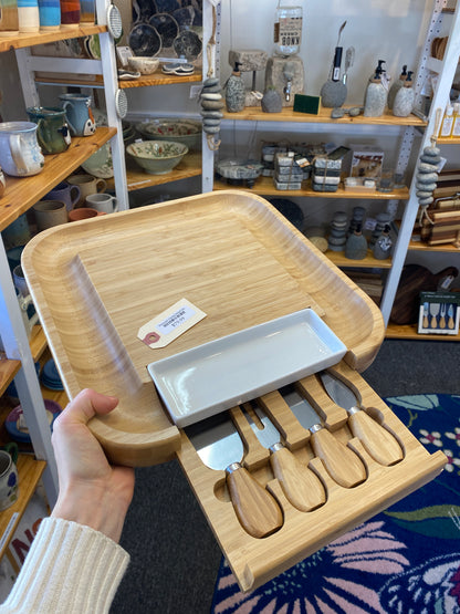 Wooden cheese board set with utensils in a store setting