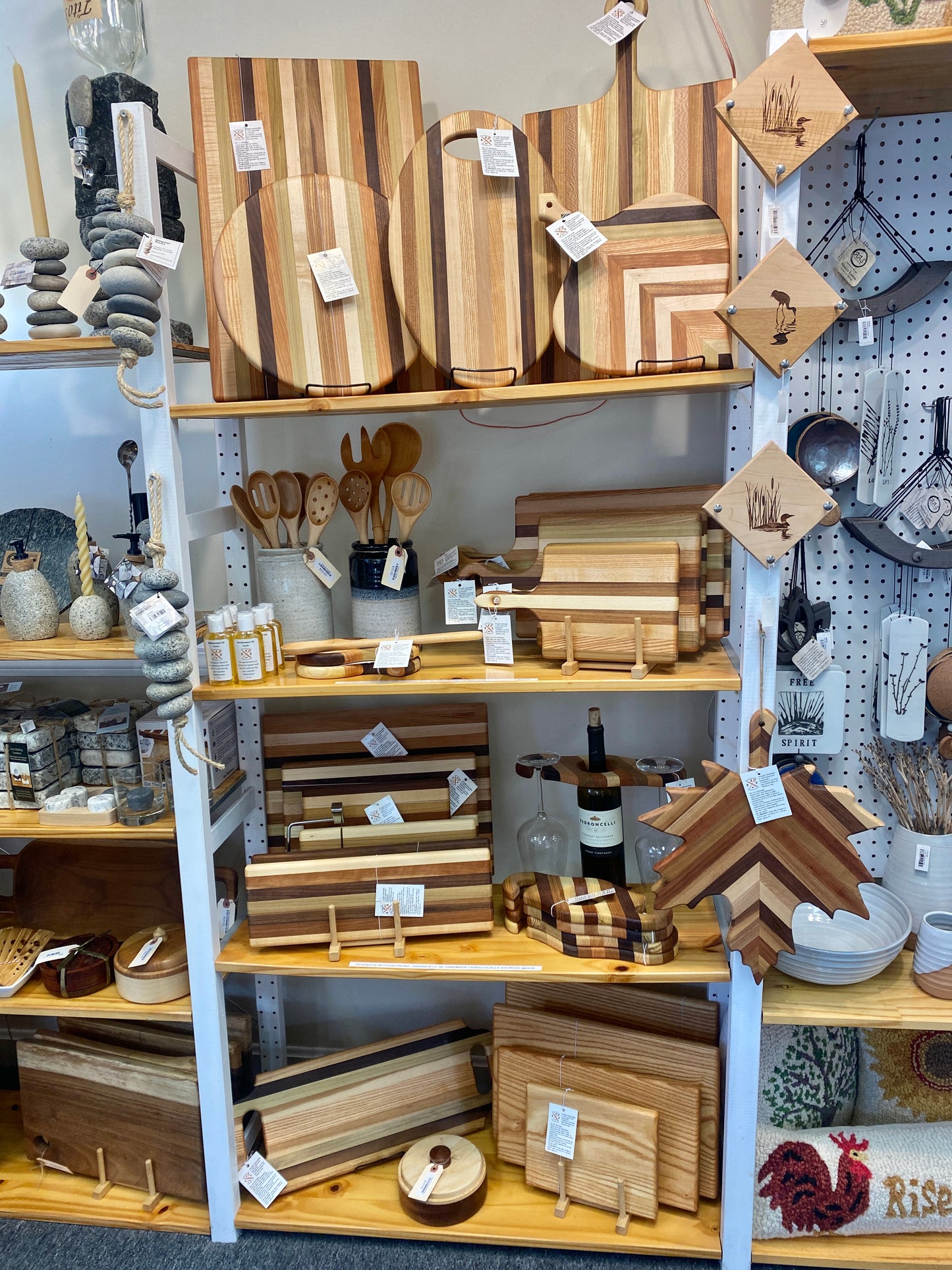 Display of wooden cutting boards and kitchen utensils on shelves in a store.