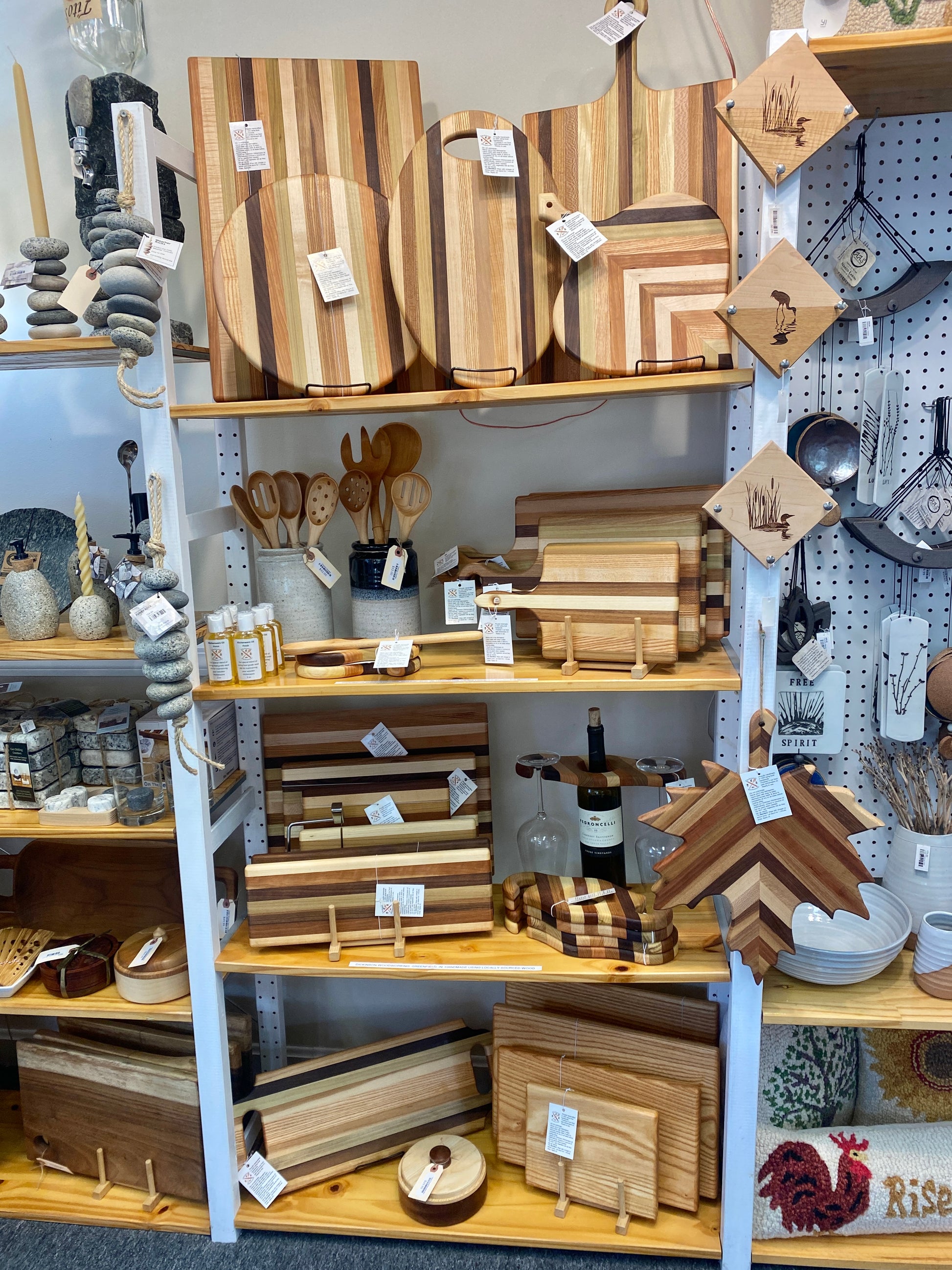Display of wooden cutting boards and kitchen utensils on shelves in a store.