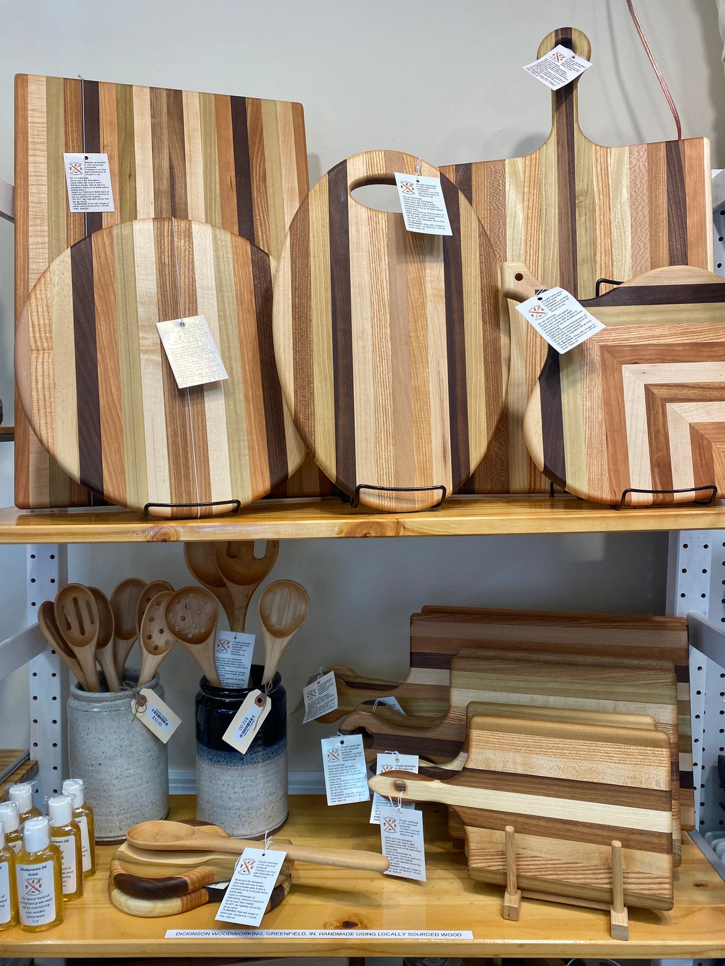 Wooden cutting boards and kitchen utensils on display in shop with price tags.