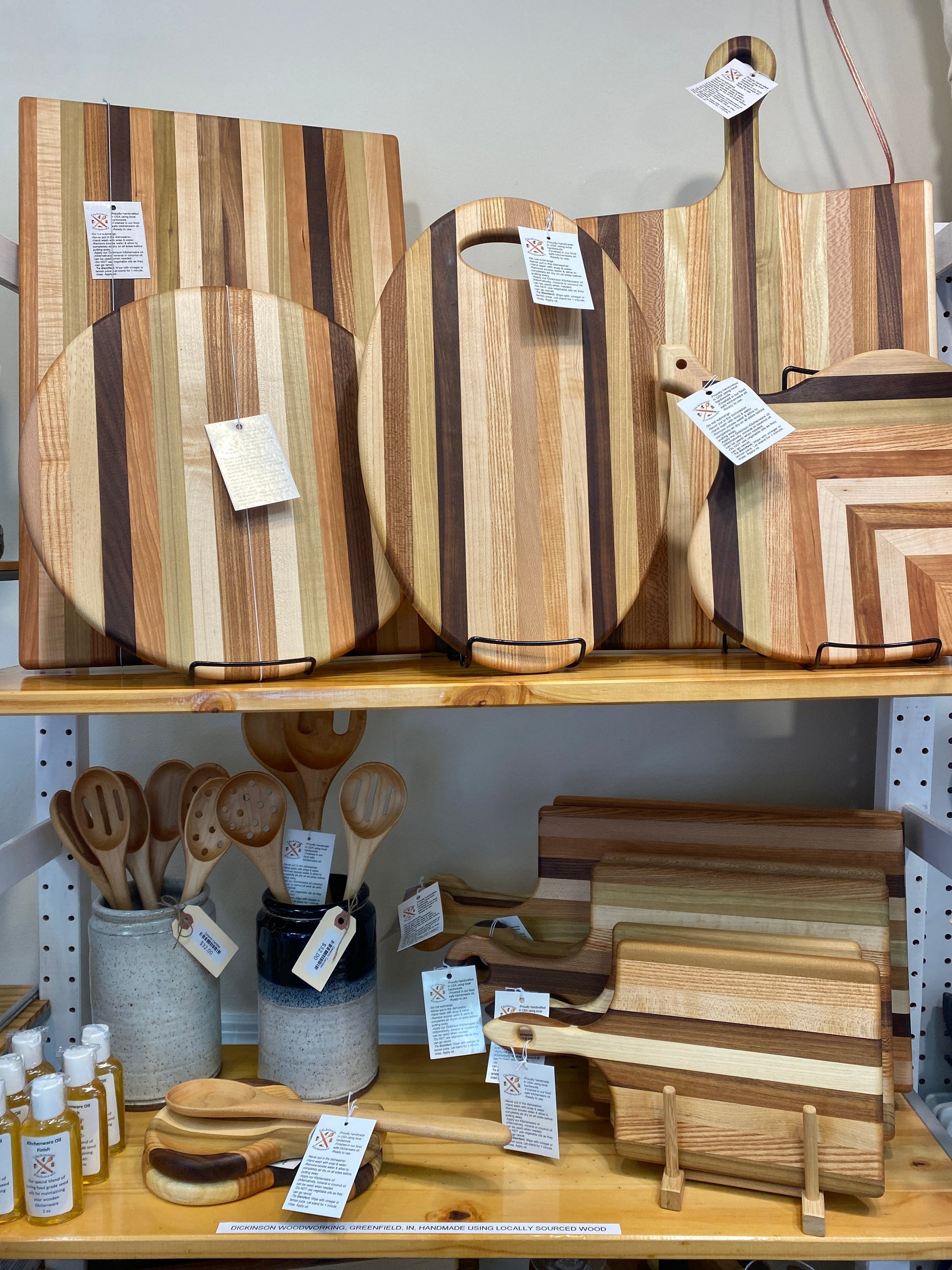 Wooden cutting boards and kitchen utensils on display in shop with price tags.