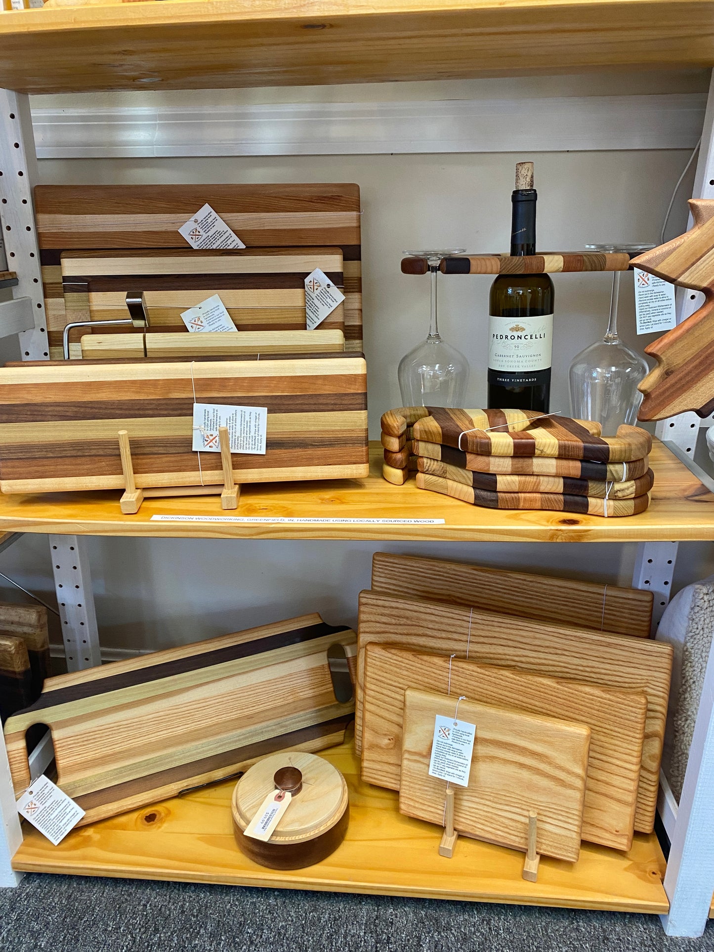 Wooden cutting boards and platters on a store shelf with price tags.