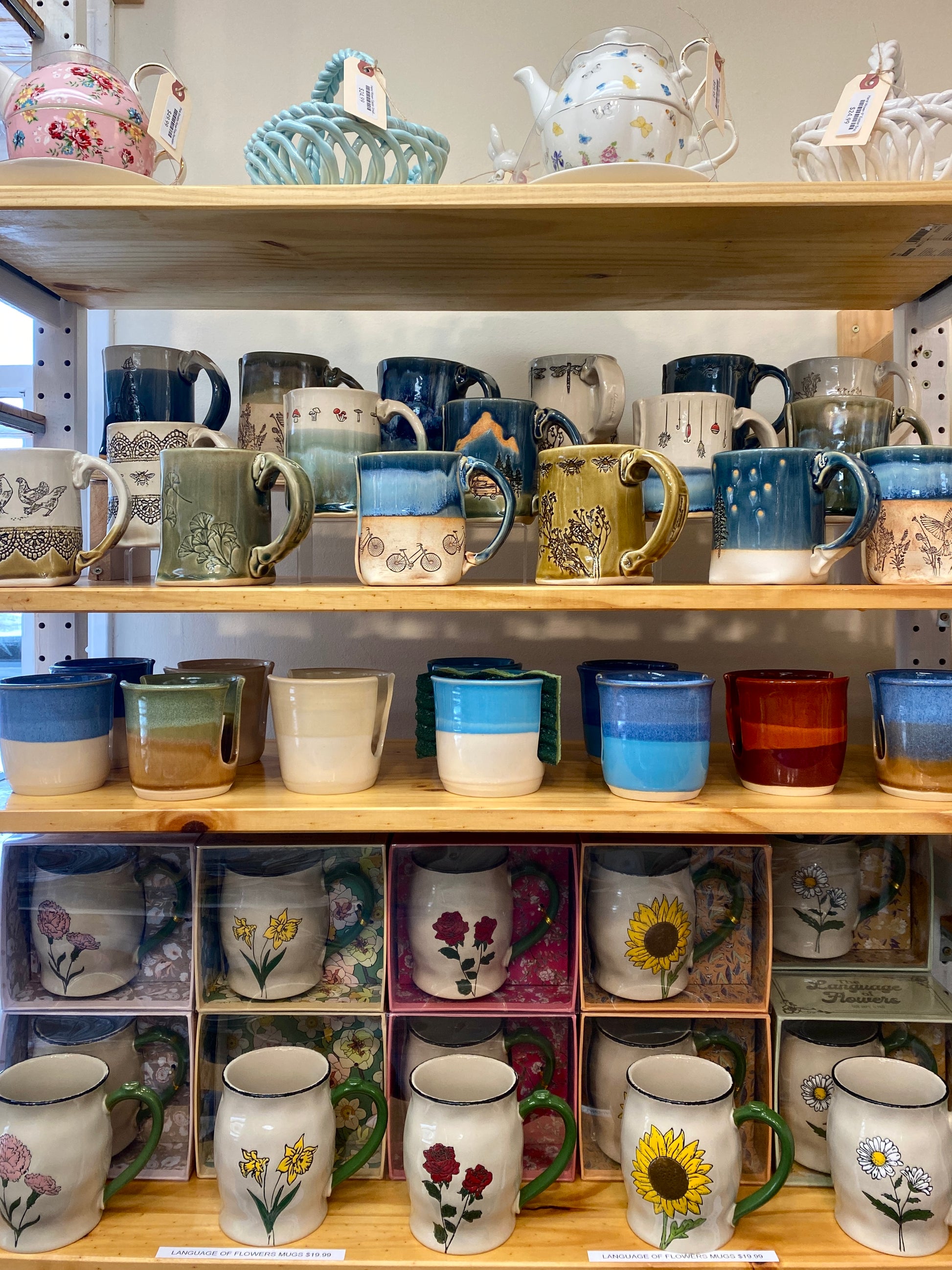 Store shelves displaying a variety of ceramic mugs and teapots with decorative designs.