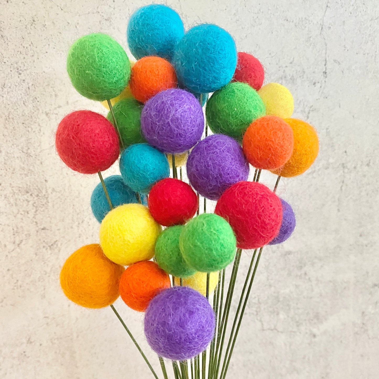 Colorful felt ball bouquet on a textured beige background