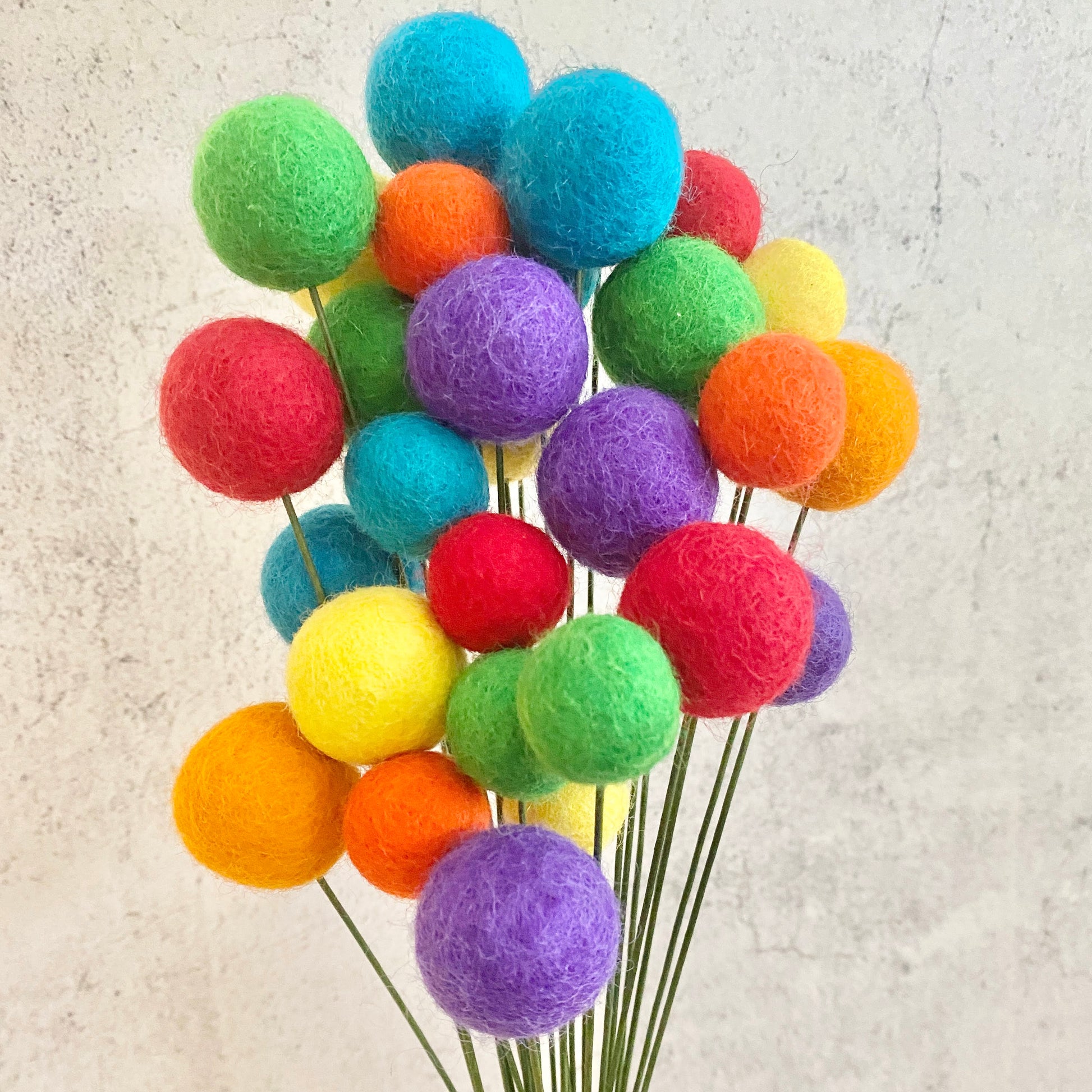 Colorful felt ball bouquet on a textured beige background