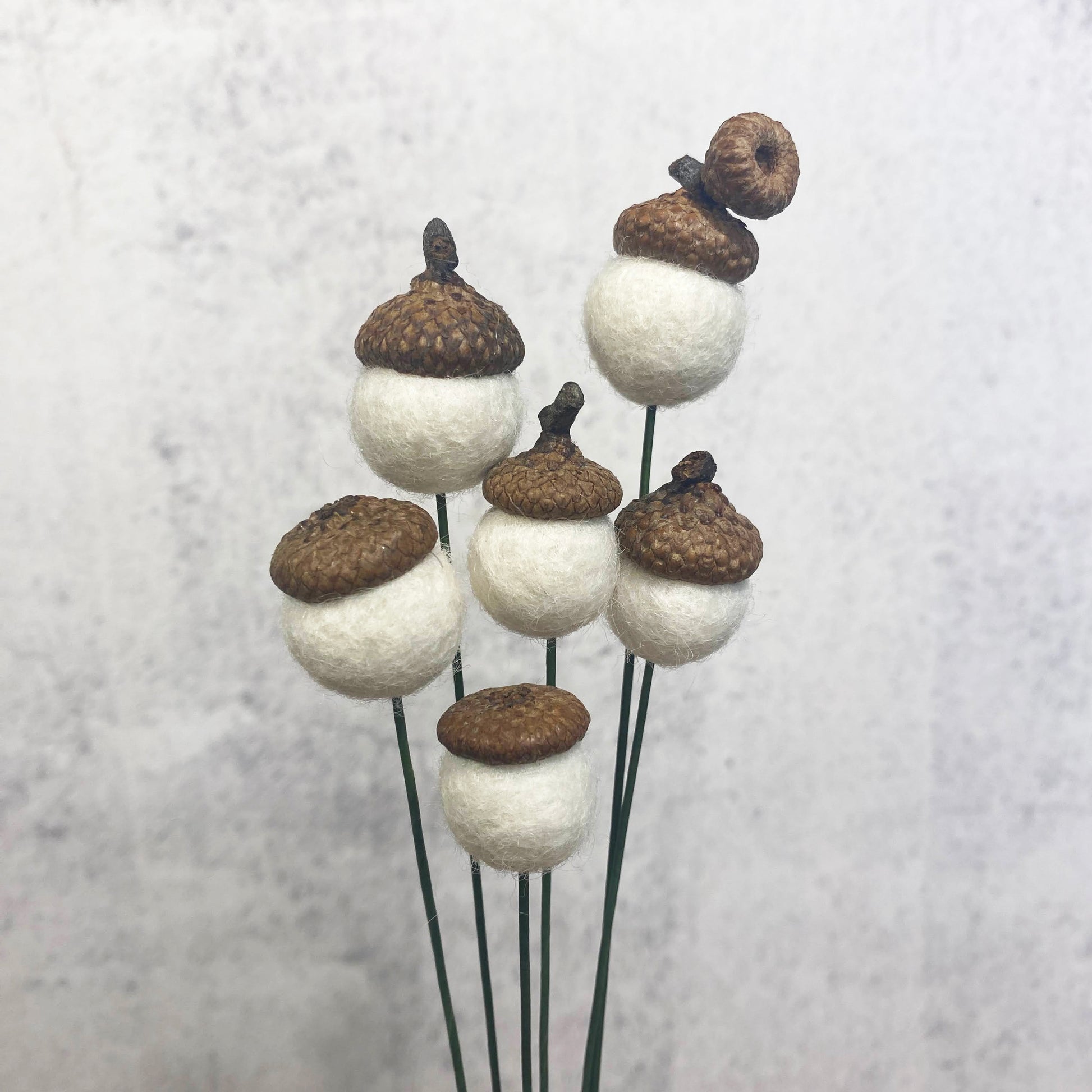 Decorative acorn-shaped objects on sticks against a light background