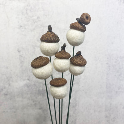 Decorative acorn-shaped objects on sticks against a light background