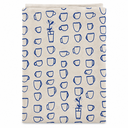 A cream colored tea towel with blue teacups design on a white background.