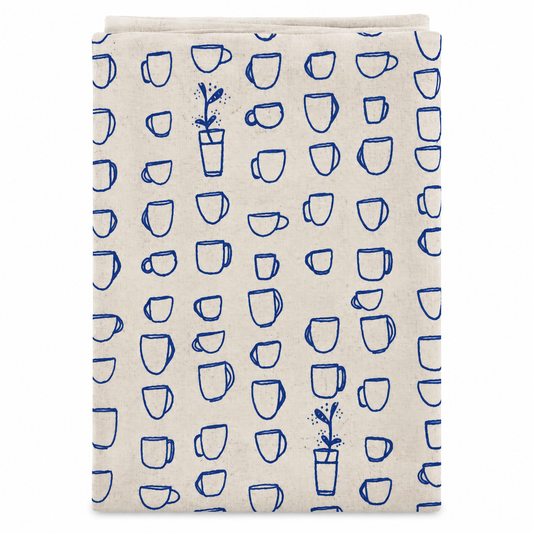 A cream colored tea towel with blue teacups design on a white background.