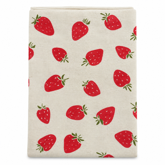 A cream colored tea towel with red strawberry design on a white background.