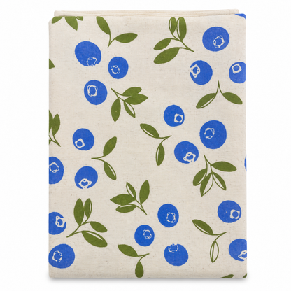 A cream colored tea towel with blueberries and green leaves design printed in black on a white background.