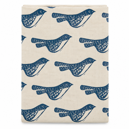 A cream colored tea towel with birds design printed in black on a white background.