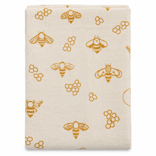A cream colored tea towel with bee design printed in gold on a white background.