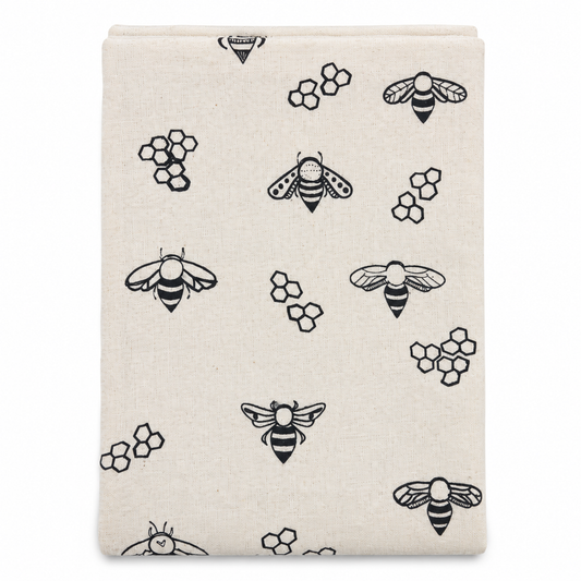 A cream colored tea towel with bee design printed in black on a white background.
