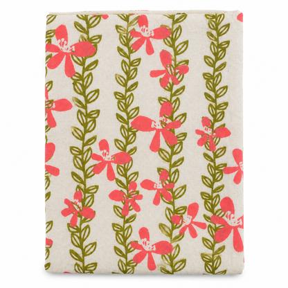 A cream colored tea towel with pink flowers and green vines design on a white background.