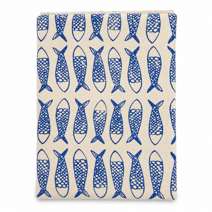 A cream colored tea towel with fish design printed in blue on a white background.