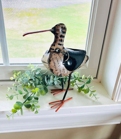 Decorative bird sculpture on a windowsill with greenery