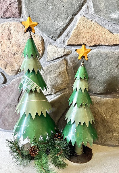 Two decorative Christmas trees against a stone wall.