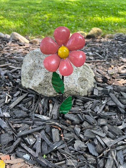 Decorative metal flower with mulch and grass in the background