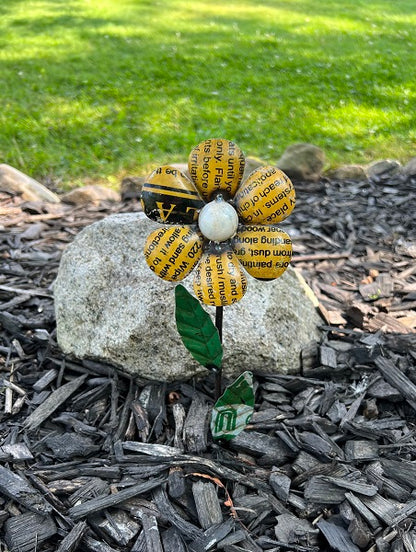 Metal flower made from recycled materials with grass and mulch in the background
