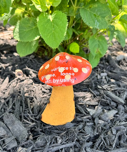 Decorative mushroom with a red cap and yellow stem on mulch