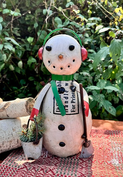 Decorative snowman figurine with a green scarf against a natural background