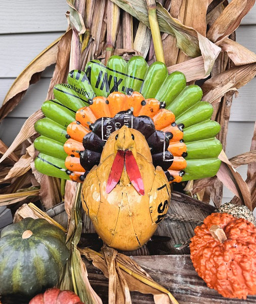 Decorative turkey, displayed outside with pumpkins and corn stalks.