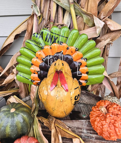 Decorative turkey, displayed outside with pumpkins and corn stalks.