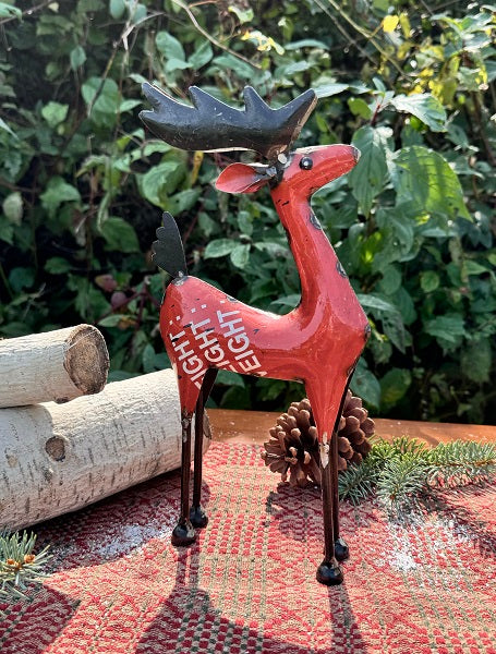 Decorative red reindeer figure with antlers on a garden surface