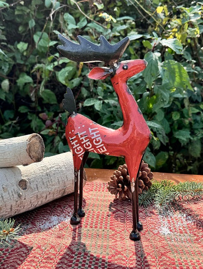 Decorative red reindeer figure with antlers on a garden surface