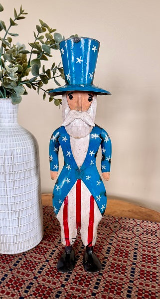 Decorative figure of Uncle Sam with a patriotic outfit, standing on a patterned table runner