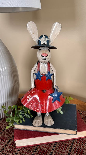 Decorative rabbit figure in a red dress with blue stars on a stack of books.
