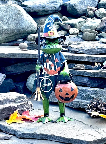 Frog statue in Halloween costume with broom and pumpkin bucket against stone background