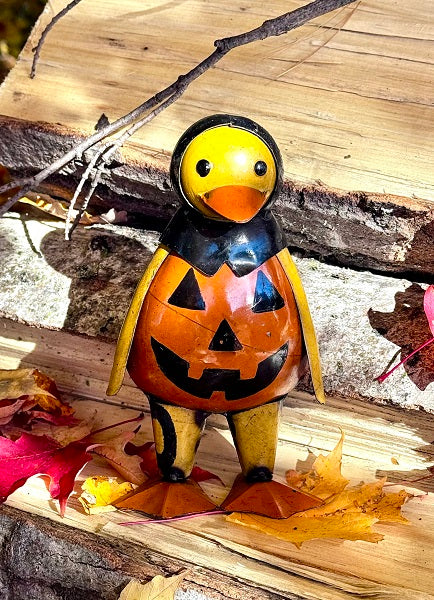 Pumpkin-shaped duck figurine on a wooden surface with leaves