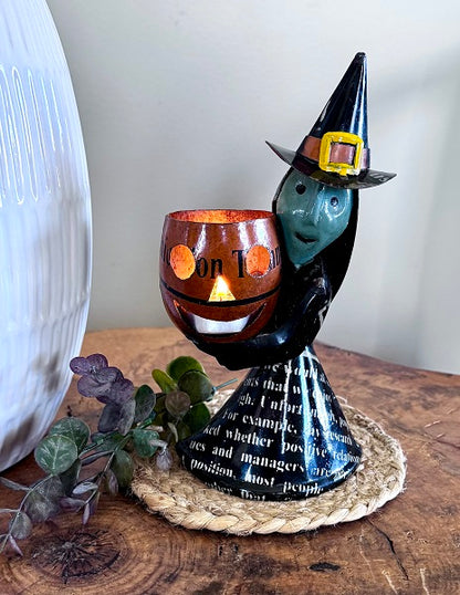 Halloween-themed decorative item with a witch hat and candle on a wooden surface.