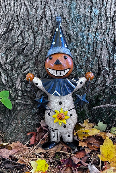 Decorative figure with a blue hat and sunflower standing against a tree trunk.