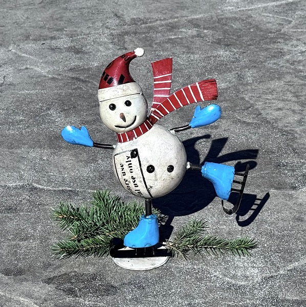 Decorative skating snowman figurine with a red hat and scarf, blue gloves, and a white ball body on a textured gray background.